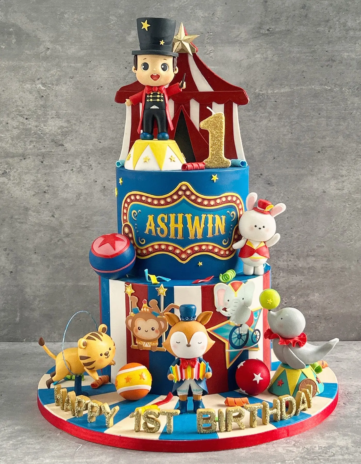 Circus-themed two-tier 1st birthday fondant cake with ringmaster topper and sculpted animals